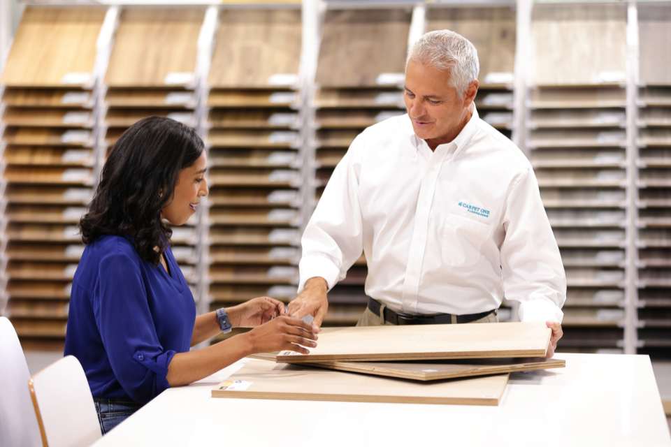 carpet one salesperson showing customer flooring samples